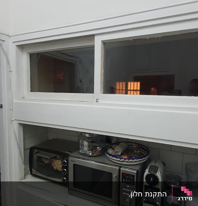 חלון זכוכית עם מסגרת לבנה מעל מדפים במטבח